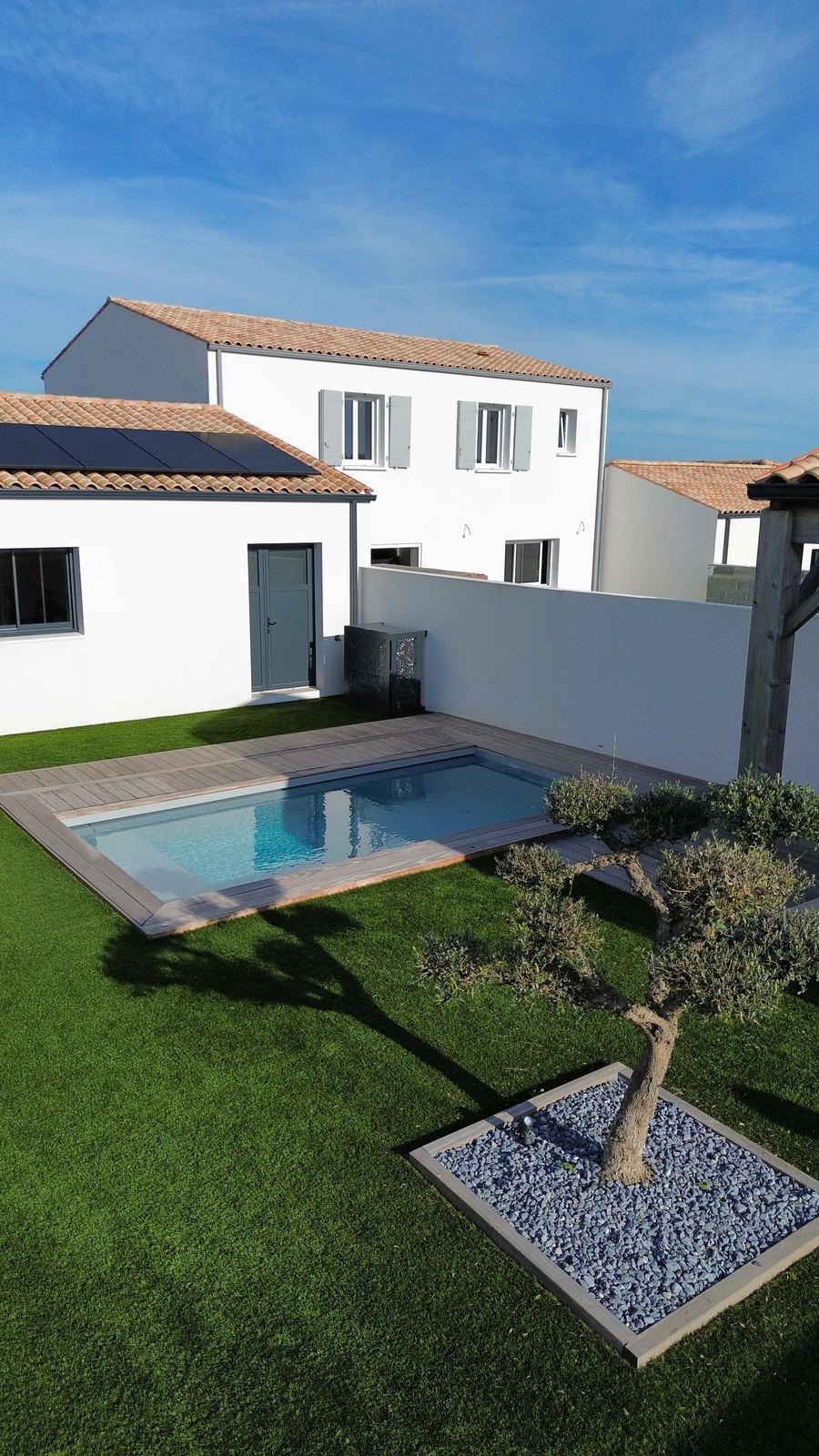 Piscine, terrasse bois et olivier en carré de galets